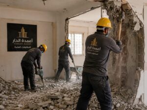 عمال تكسير أحياء الرياض يقومون بهدم جدار خرساني قديم وترميم المبنى